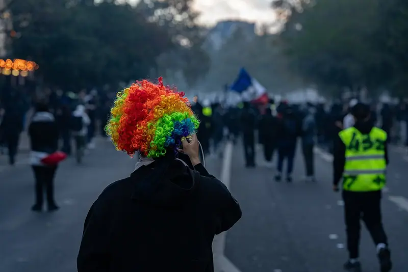 Демонстранти в Париж по време на протеста на 17 октомври 2026 г.; участник носи многоцветна перука.