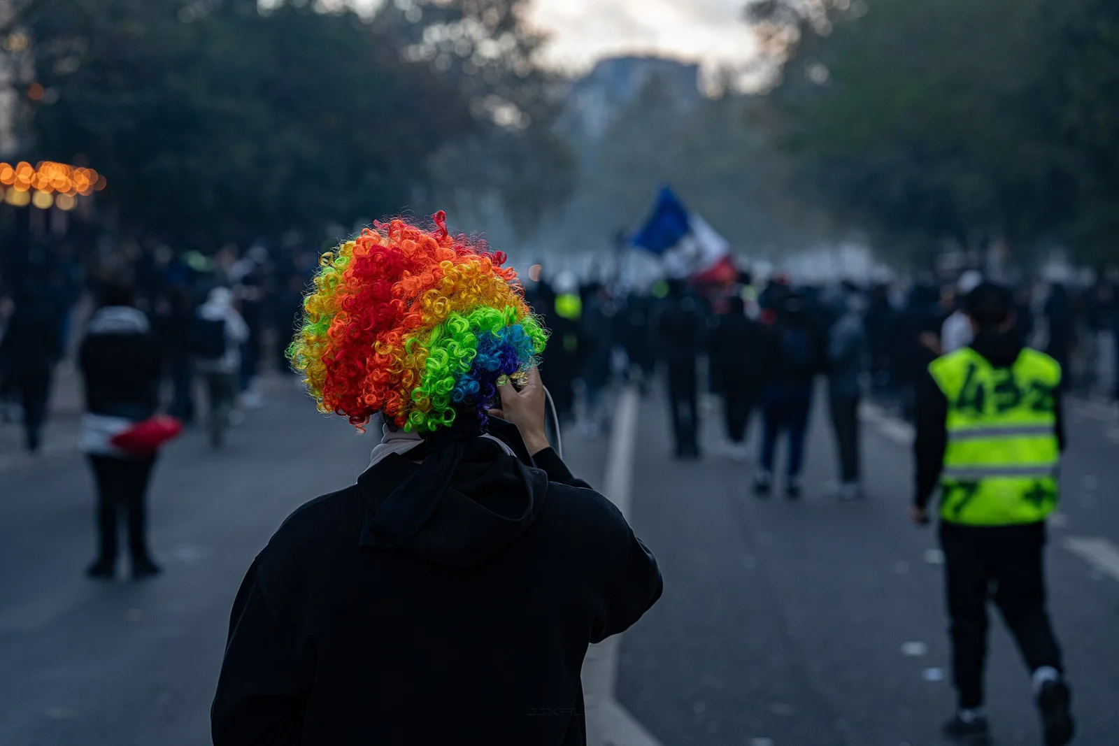 Демонстранти в Париж по време на протеста на 17 октомври 2026 г.; участник носи многоцветна перука.
