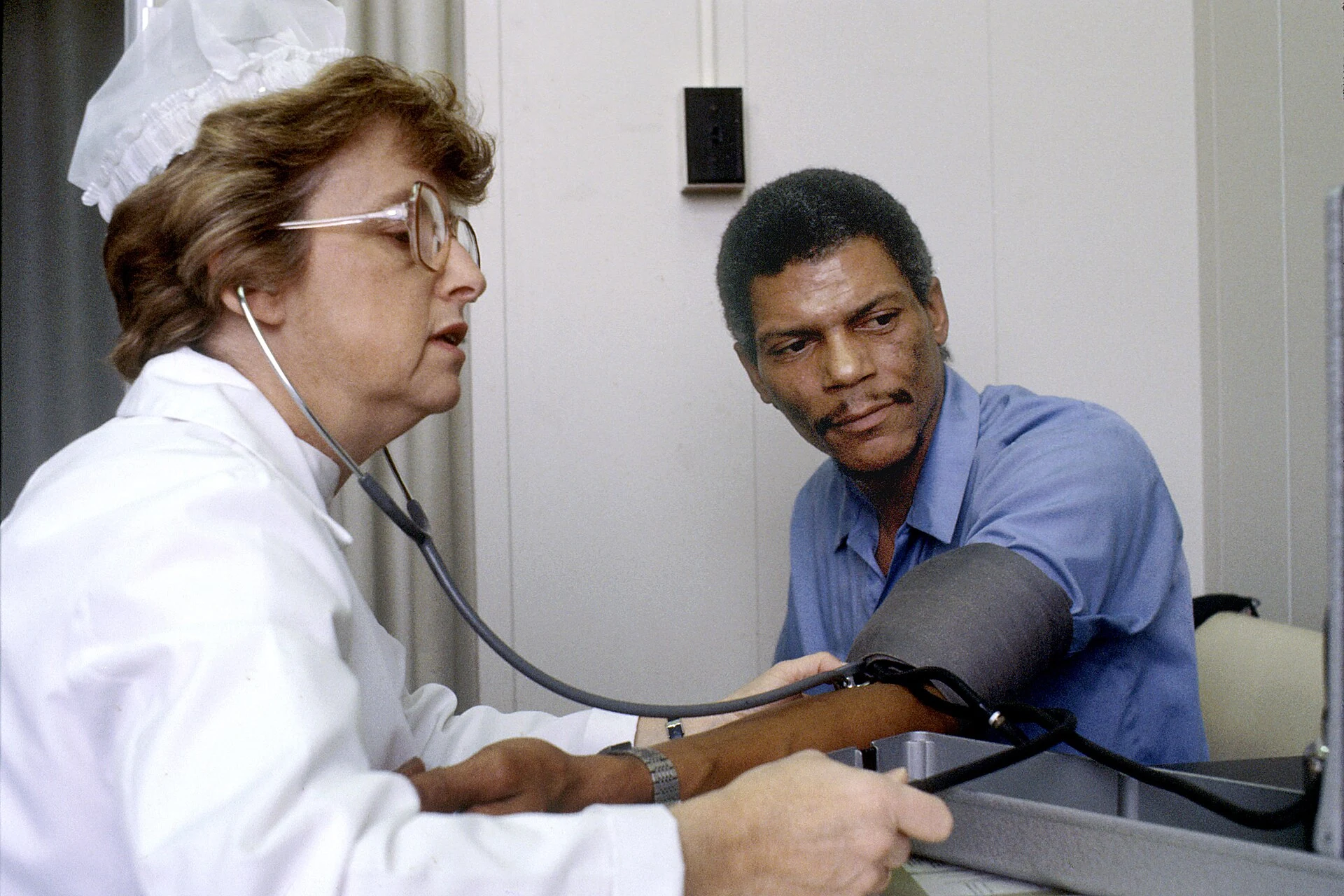A nurse measures a seated patient’s blood pressure with an arm cuff.