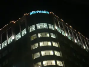 Осветен надпис Microsoft върху офисна сграда през нощта.