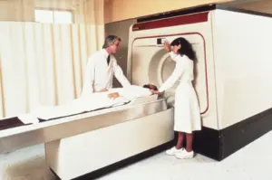 Лекар и медицинска сестра до пациент при MRI скенер.