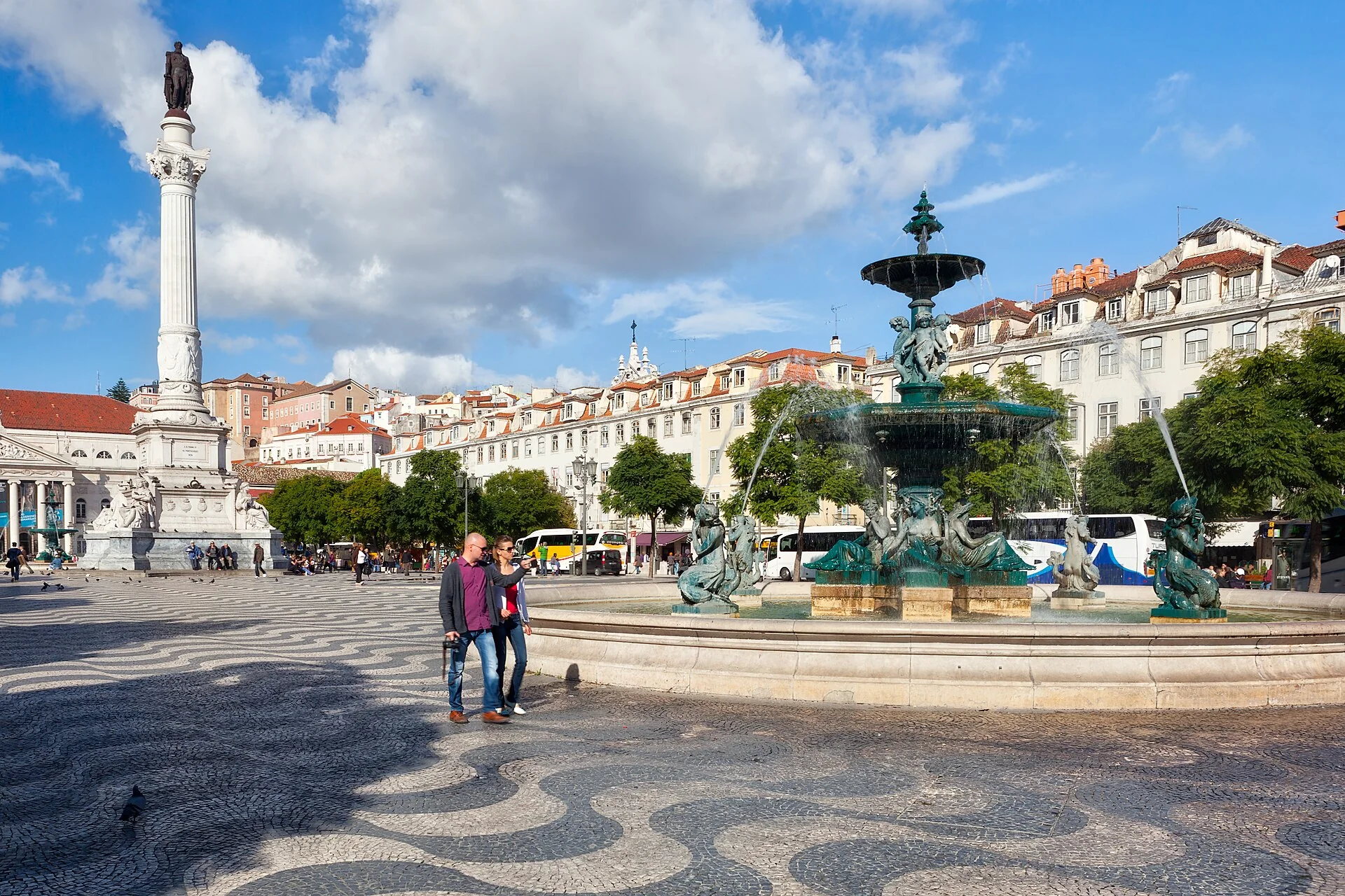 Rossio Square in Lisbon with patterned paving, a fountain and surrounding buildings.